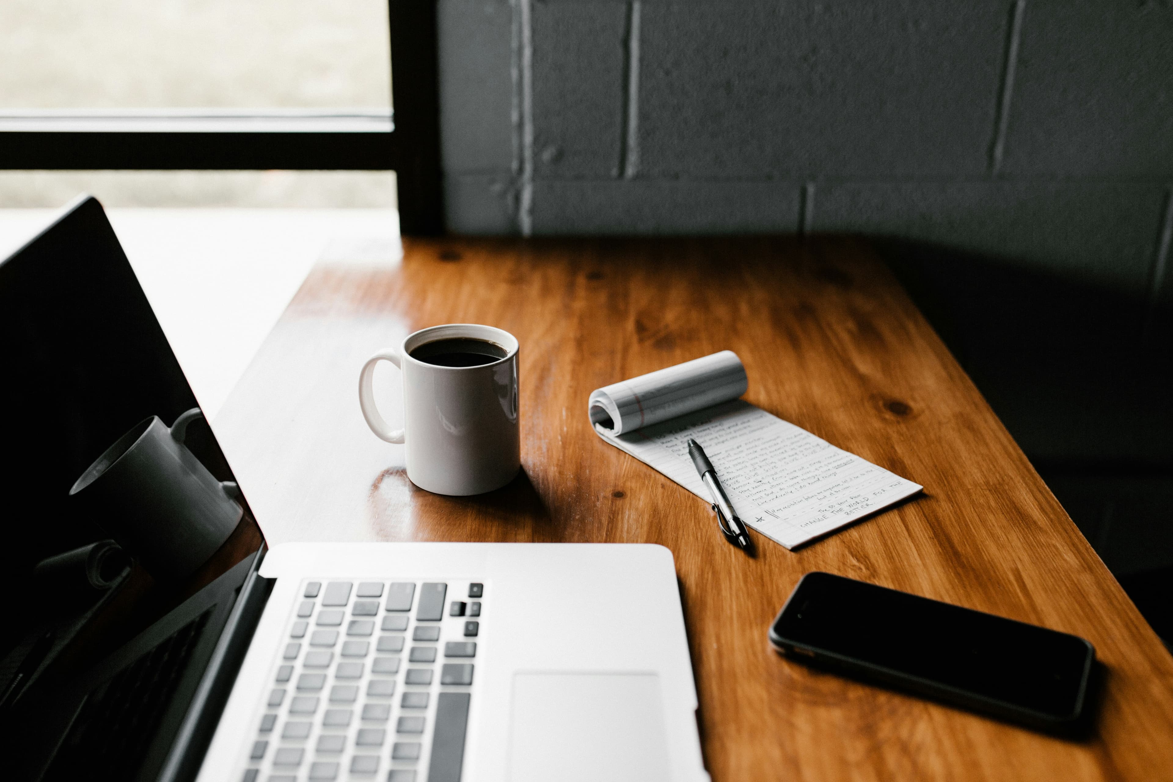 Personne qui travaille sur un ordinateur portable posé sur un bureau en bois