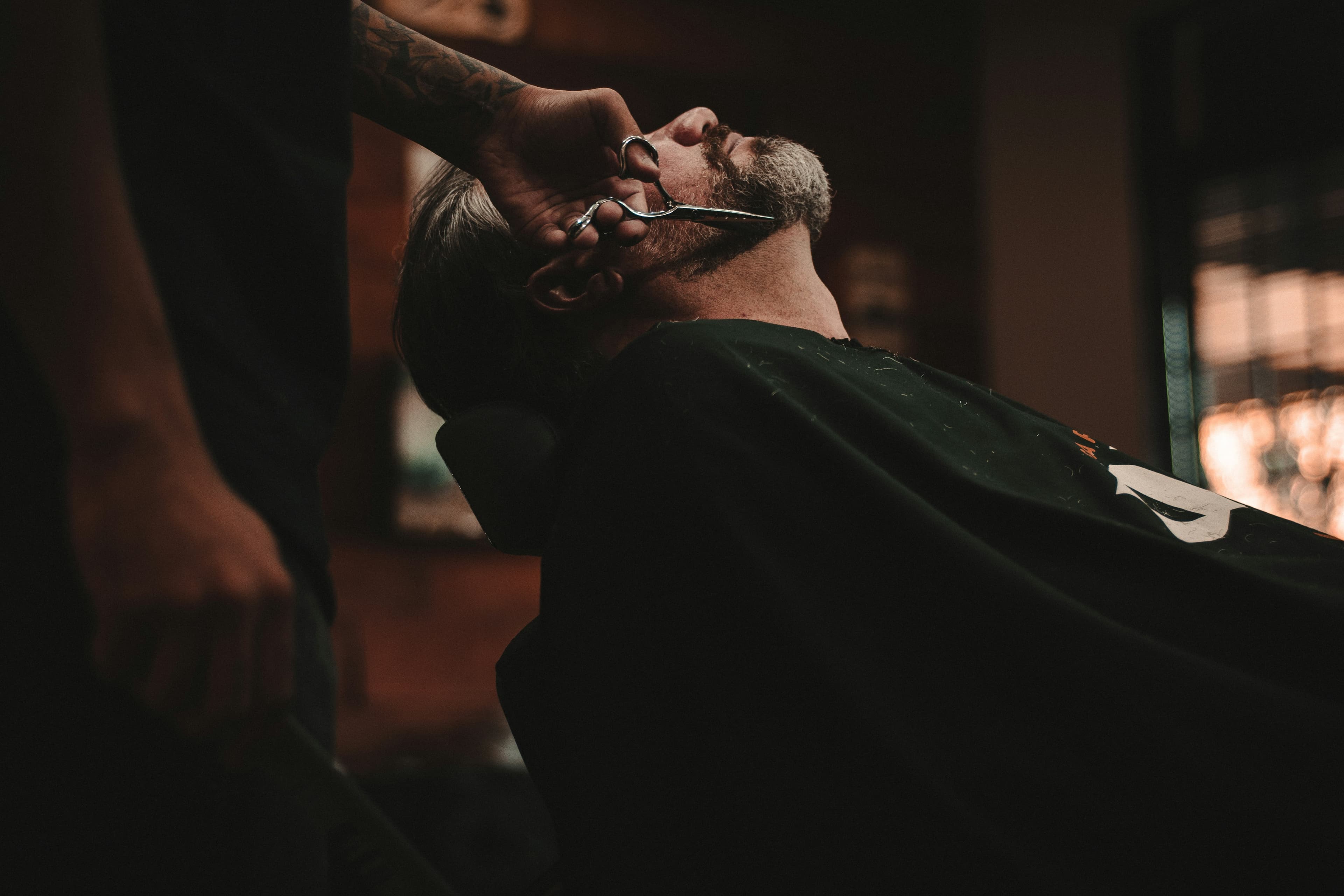 Barbier qui réalise une coupe dégradée à un client dans un barbershop