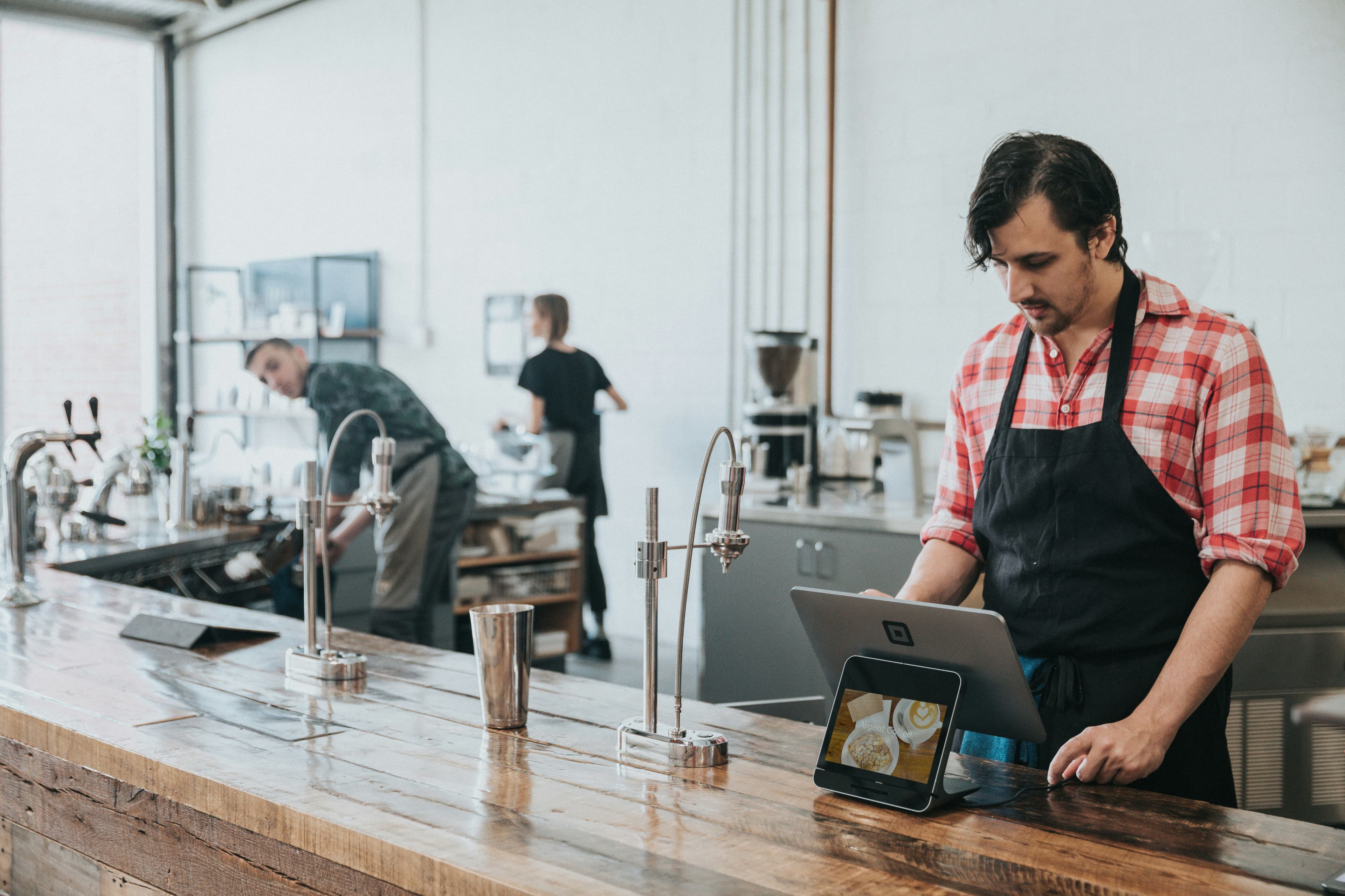 Commerçant qui enregistre une réservation sur une tablette à son comptoir